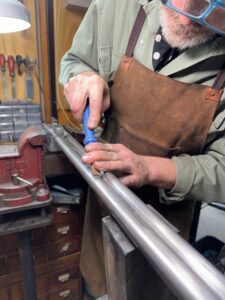 Gunsmith hand-filing a rifle barrel held in a bench vise in the Black Range Firearms workshop